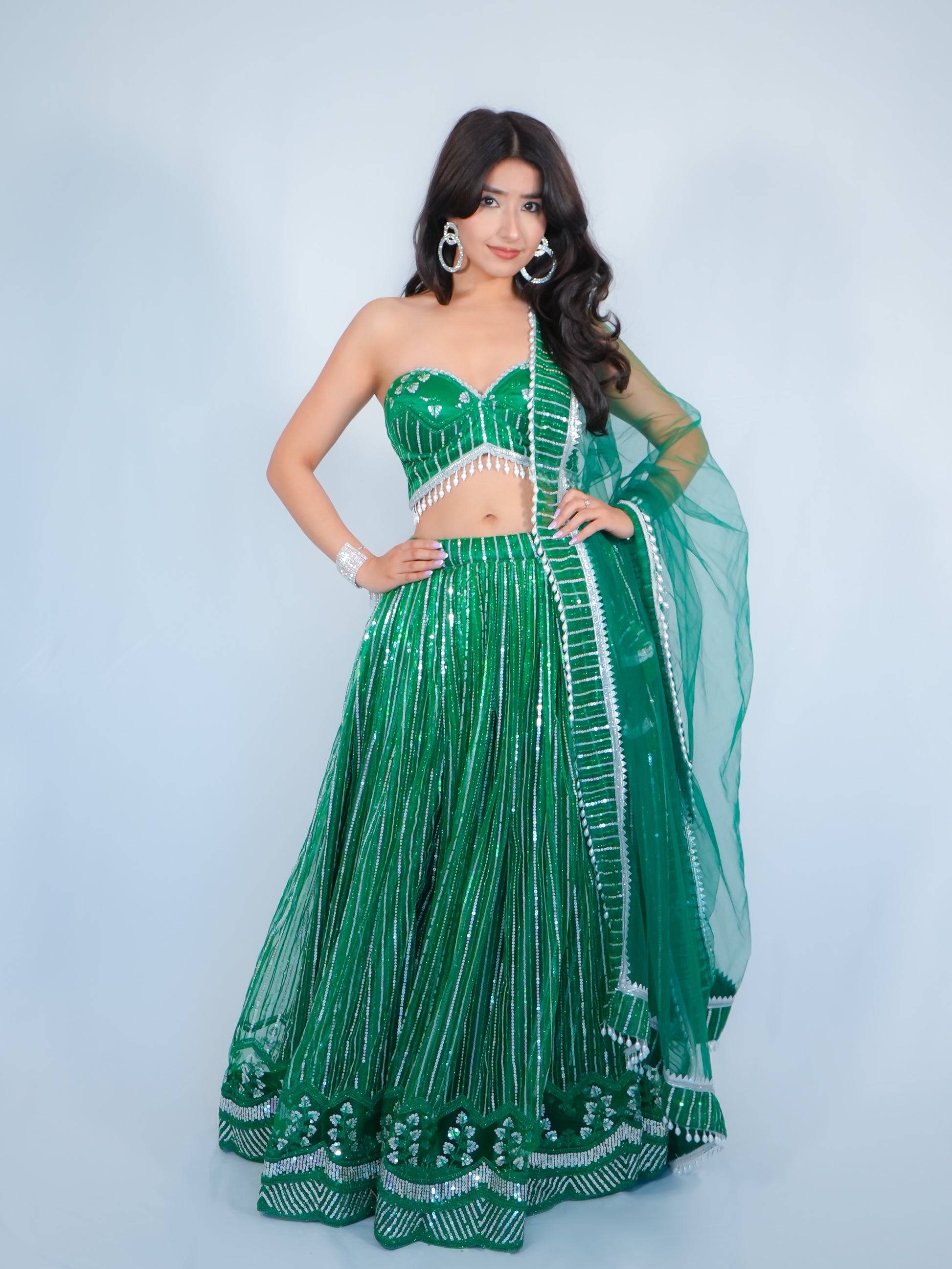 Woman wearing a green traditional outfit with white detailing on a light gray background