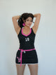 Black lycra bodycon mini dress for women featuring pink contrast detailing and sporty number print design. Made from premium stretchable lycra fabric, this dress offers a smooth, flexible fit that enhances curves while ensuring all-day comfort. The sleeveless design, mini length, and stylish waist tie add a bold and trendy touch. Perfect for club wear, parties, night outings, and fashion shoots, this outfit delivers a sporty yet glamorous vibe. Inspired by modern Bollywood style, it pairs effortlessly with 